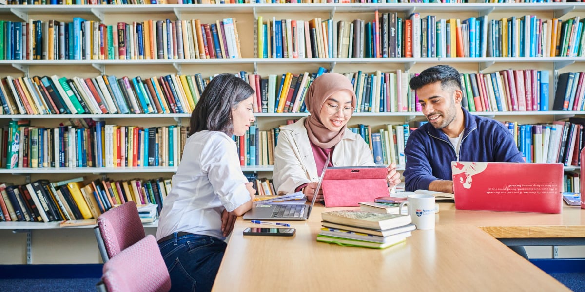 Three students studying in a University library.
