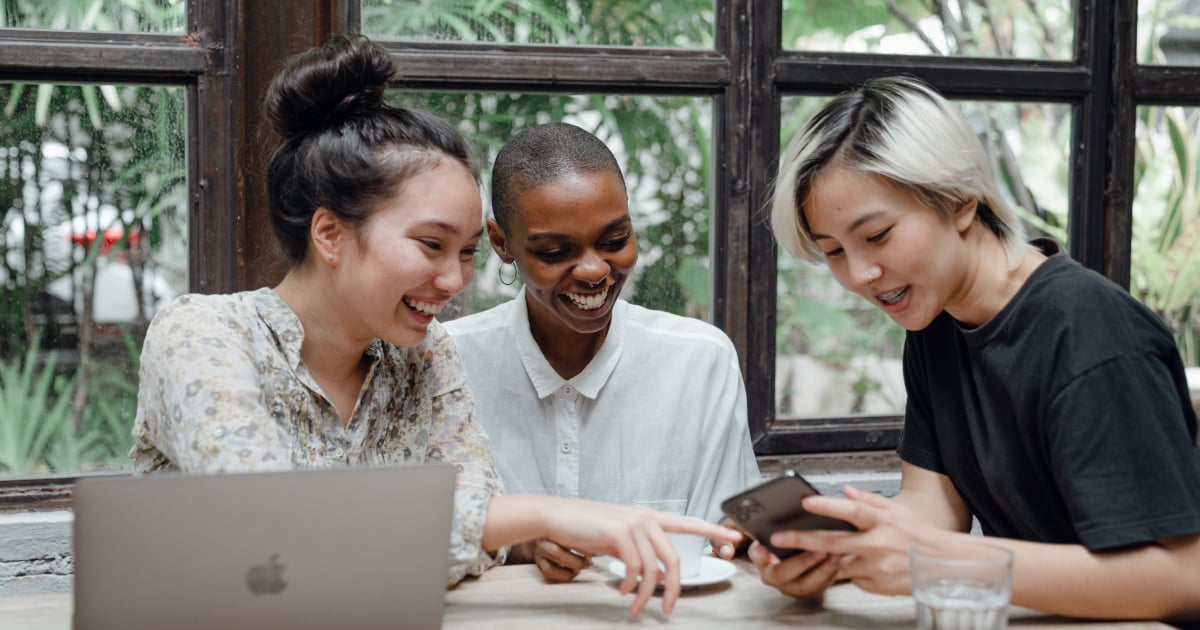 Three women looking at laptop and mobile