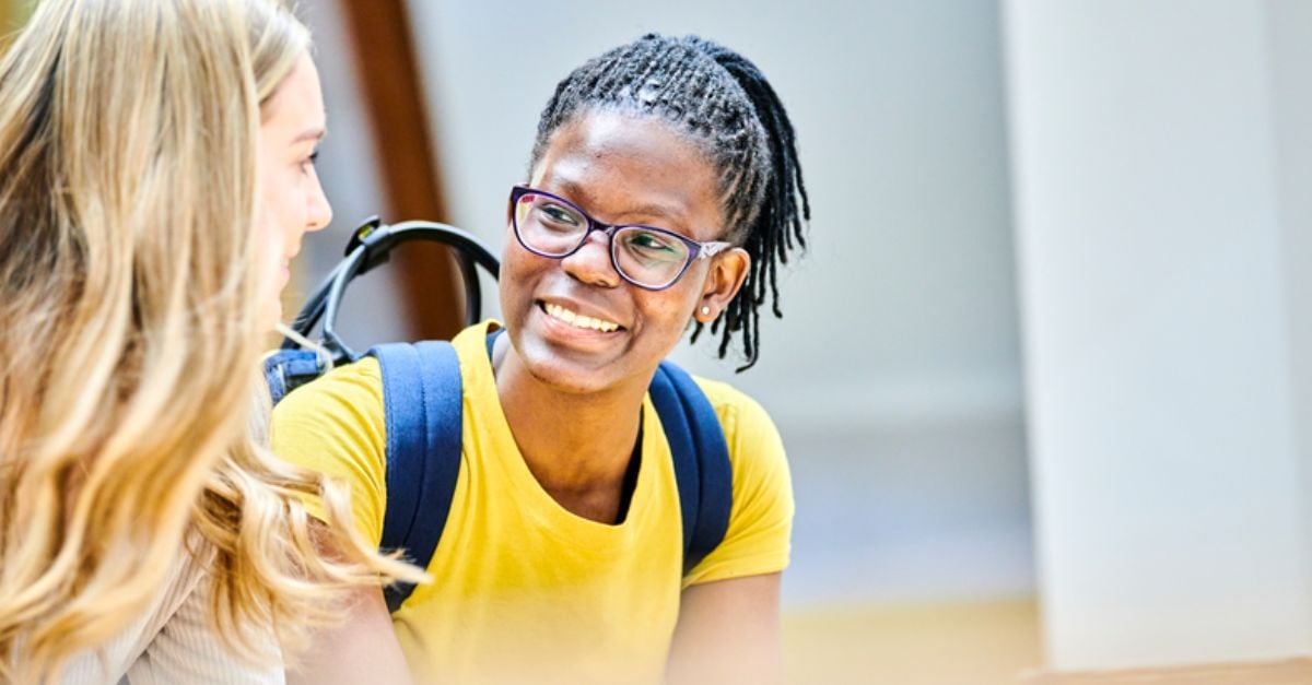 Female student smiles at another student in university hall 