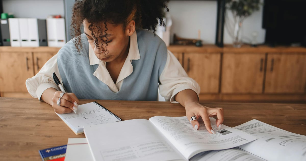 Student revising by making notes from a text book
